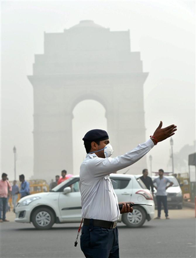 A traffic policeman wearing mask controls traffic at India Gate amid smog and air pollution that reached high levels, in New Delhi on Sunday. PIC/PTI