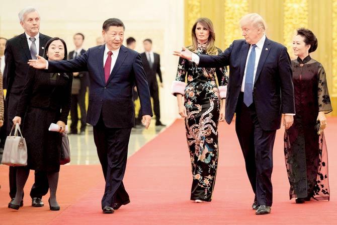 Donald Trump gestures towards Xi Jinping, as US First Lady Melania Trump and Xi’s wife Peng Liyuan look on, at the Great Hall of the People in Beijing on Thursday. PIC/AFP