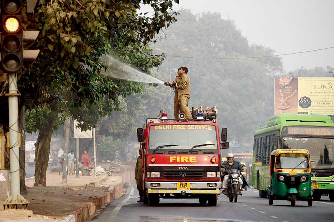 Firefighters spray water onto trees at the roadside in a bid to curb air pollution in New Delhi on Thursday. Delhi is now the world