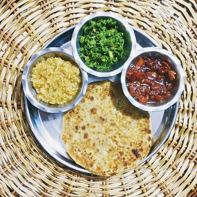 A typical meal from Mithila consisting of (clockwise from left) gud ki kheer, mooli ka saag, tamatar ki mithi chutney and mooli ka paratha,  (below) litti chokha