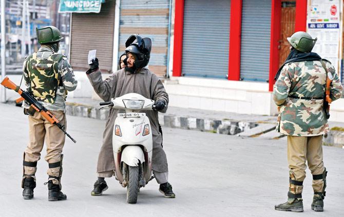 Troopers stop a motorcyclist the day after a gunfight between terrorists and security forces, yesterday in Srinagar. PIC/AFP