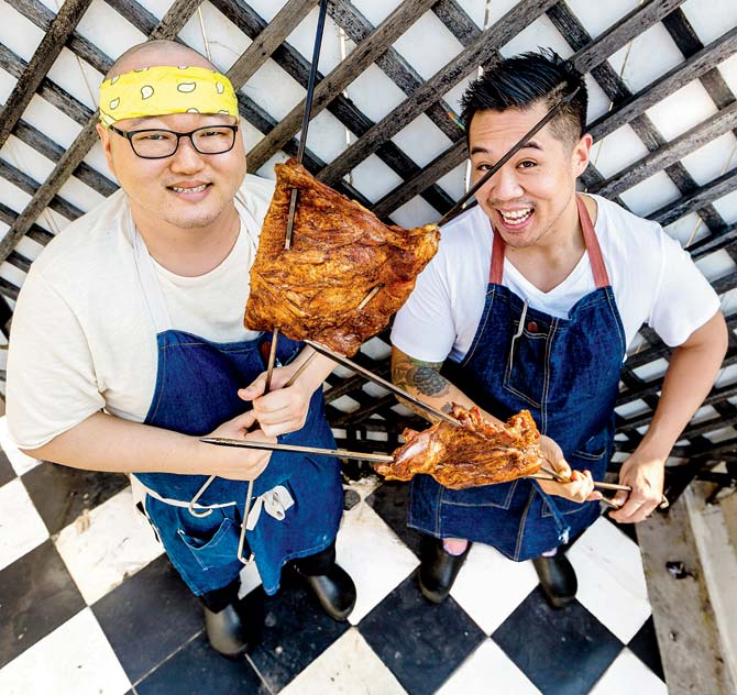 Chefs Boo Kim and Kelvin Cheung with meat barbecued on their smoker grill
