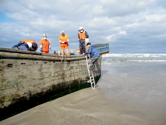 Coast guard officers inspecting  a battered wooden boat where eight bodies were found. pic/afp