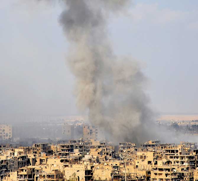 Smoke billows from the Syrian city of Deir el-Zour during an operation by Syrian government forces against IS group jihadists on Thursday. Pic/AFP