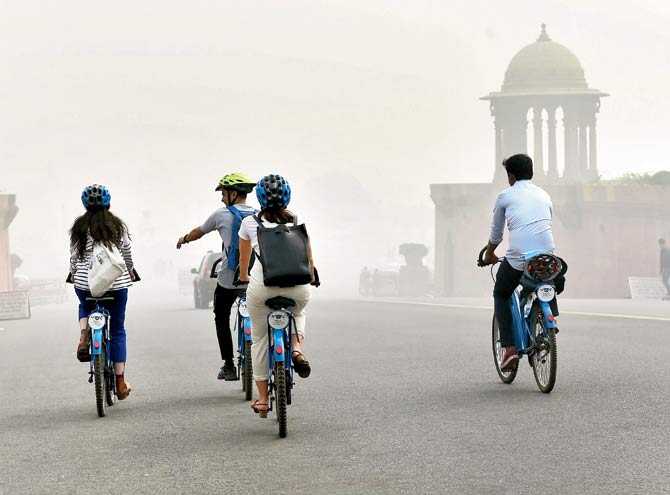 Teenagers venture out on their bicycles amid heavy smog and air pollution that reached high levels in New Delhi on Sunday. Pic/PTI