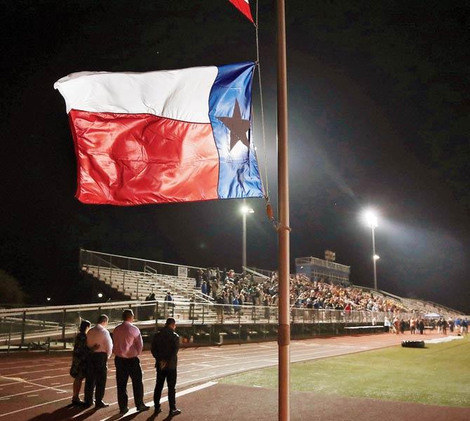 A Texas flag flies at half mast during a prayer service at the  La Vernia High School. PIC/AFP