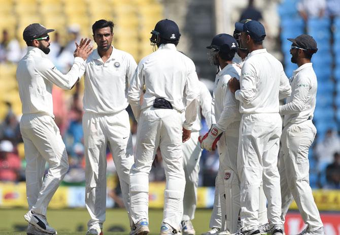 Ravichandran Ashwin (2L) celebrates with captain Virat Kohli (L) and teammates after taking the wicket of Sri Lankan batsman Dilruwan Perera