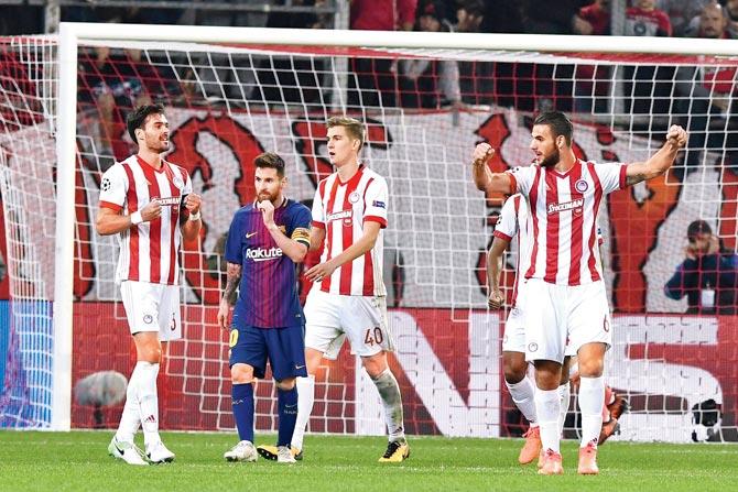 Olympiacos players celebrate around Barcelona’s Lionel Messi after their goalless draw in Piraeus near Athens last night. Pic/ AFP