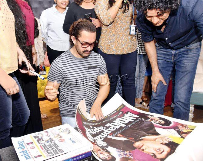 Aamir Khan signs on a memorabilia, the original poster of his 1994 release, Andaz Apna Apna
