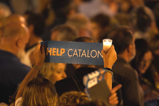 A woman holds a candle and a placard reading "Help Catalonia" during candle-lit demonstration in Barcelona against the arrest of two Catalan separatist leaders on October 17, 2017. Catalonia braced for protests after a judge ordered the detention of two powerful separatist leaders, further inflaming tensions in the crisis over the Spanish region