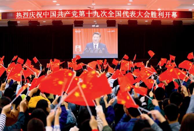 College students wave national flags as they watch the opening of the 19th Communist Party Congress in Huaibei on Wednesday. Pic/AFP