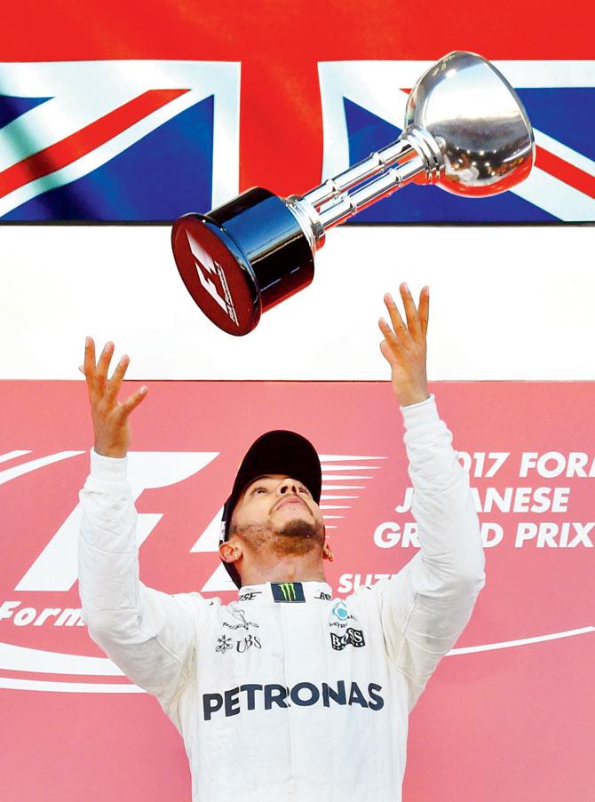 Mercedes driver Lewis Hamilton with the Japanese Grand Prix  trophy atop the victory podium in Suzuka yesterday. Pic/AFP