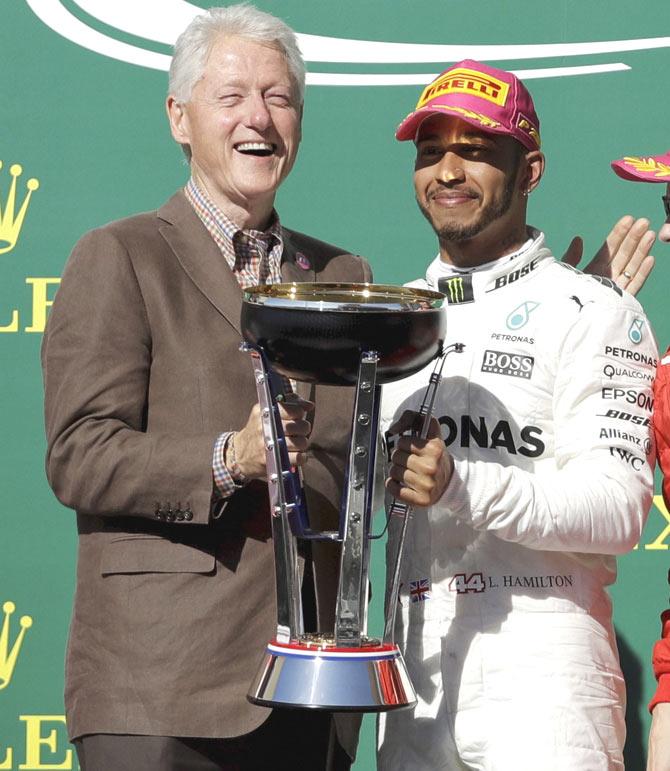 Former President Bill Clinton, left, poses with Mercedes driver Lewis Hamilton, of Britain, right, after Hamilton won the Formula One U.S. Grand Prix auto race at the Circuit of the Americas, Sunday, Oct. 22, 2017, in Austin, Texas. Pic/AP/PTI
