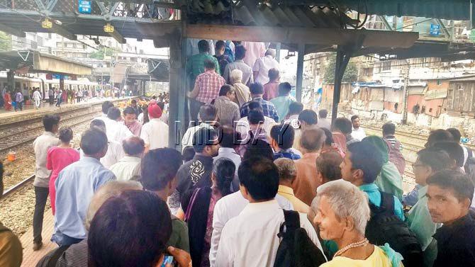Commuters crowd at a narrow staircase at Masjid Bunder station that leads to a narrower foot overbridge