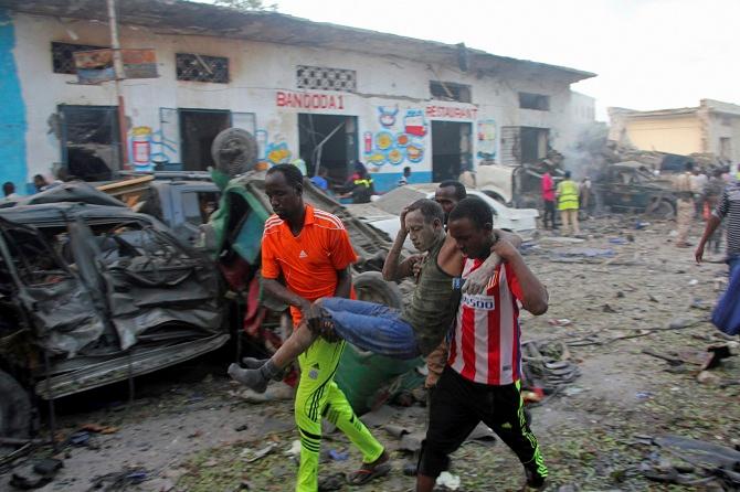 Somalis carry away a man injured after a car bomb was detonated in Mogadishu, Somalia 