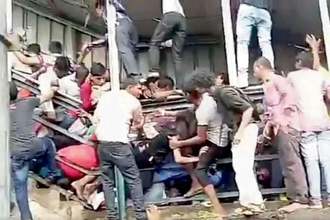 Locals climb on to the narrow foot over-bridge at Elphinstone this morning during rush hour to rescue injured commuters wedged in the railing