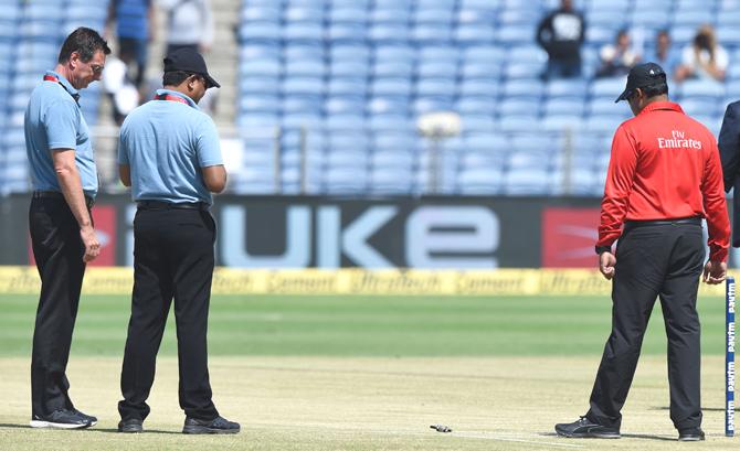 On field umpire Rod Tucker (L) of Australia and Chettithody Shamshuddin (C) of India watch as reserve umpire Nitin Menon of India tosses a bail to inspect the pitch ahead of the 2nd one day international (ODI) cricket match between India and New Zealand at The Maharashtra Cricket Association Stadium in Pune on October 25, 2017. India