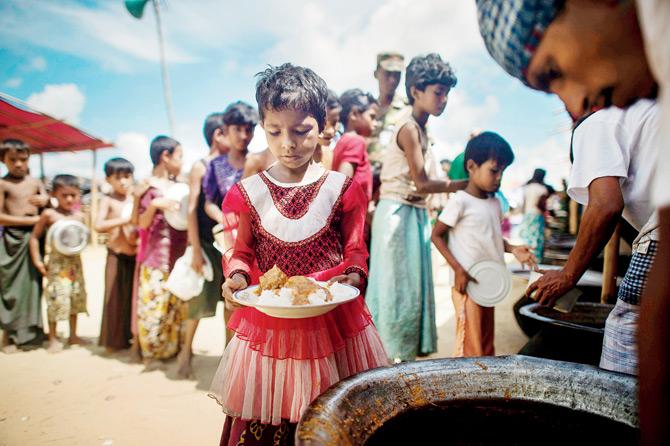 Rohingya refugees line up to receive food at Balukhali refugee camp near the town of Gumdhum in Cox