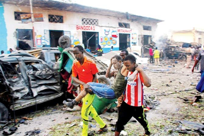 Somalis carry away an injured man after the car explosion