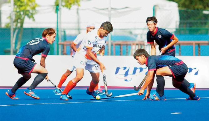 An India player (white jersey) and his Japan counterparts battle for possession in the Sultan of Johor Cup match yesterday. Pic/PTI
