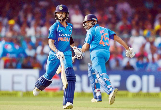 Virat Kohli (left) and Rohit Sharma take a single during their 230-run partnership for the second wicket against NZ yesterday. Pic/AFP