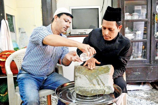 Kazim Ahmedji and Shakeb Ahmedji washing a stone at the Shaykh Misri Dargah they believe to be 500 years old and indicative of the era in which this saint came here. Pics/Falguni Agrawal