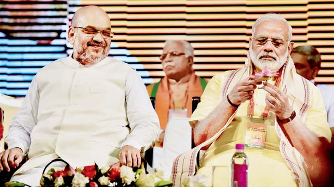 Prime Minister Narendra Modi holds a lotus as BJP president Amit Shah looks on during the party
