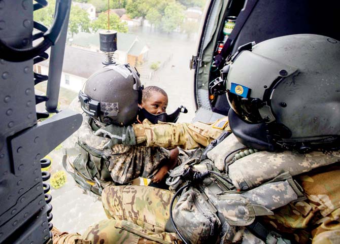 A sergeant hoists a child rescued from Port Arthur onto a Black Hawk helicopter. Pics/AFP, AP