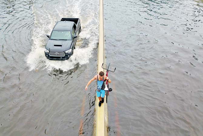 A man walks on a divider while carrying his bicycle in the aftermath of Hurricane Maria in Puerto Rico. Pic/AFP