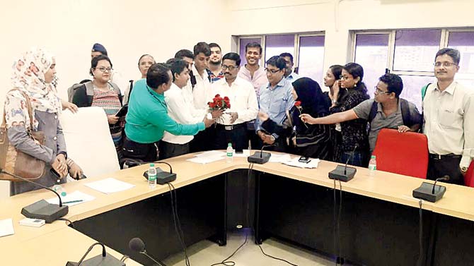 Students give roses to MU director of examinations, Dr Arjun Ghatule, to register their protest