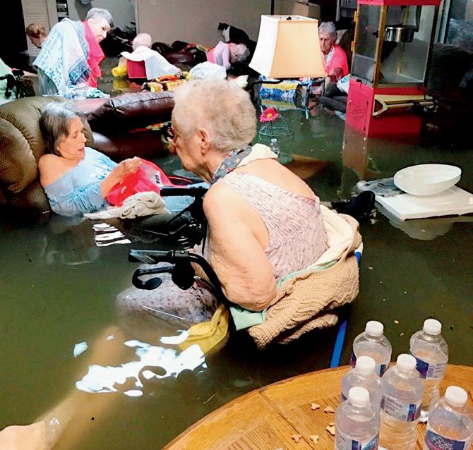 People sit in waist-deep flood waters caused by Harvey. Pic/AP