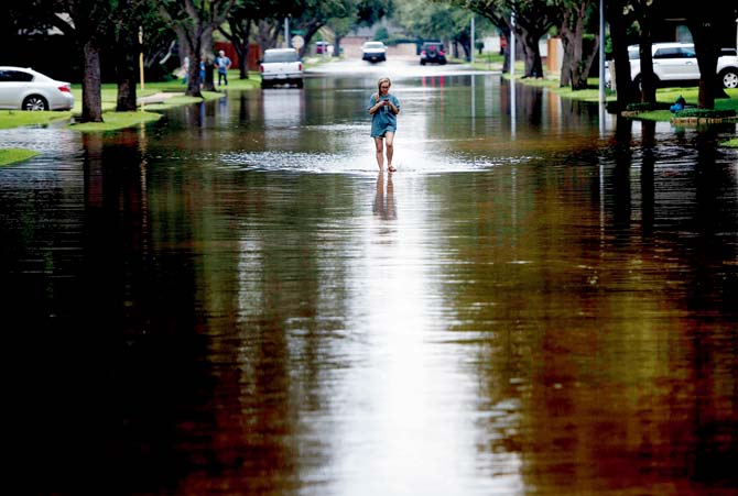 A woman walks on a flooded road in Houston