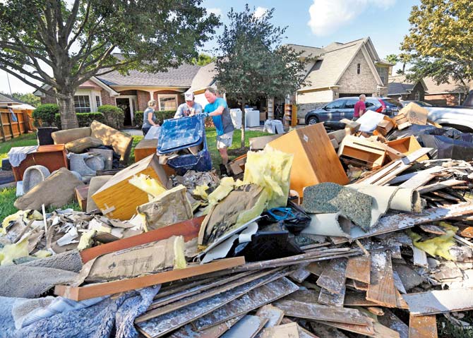 Members of a family remove debris and damaged items from their home in Houston. Pic/AFP