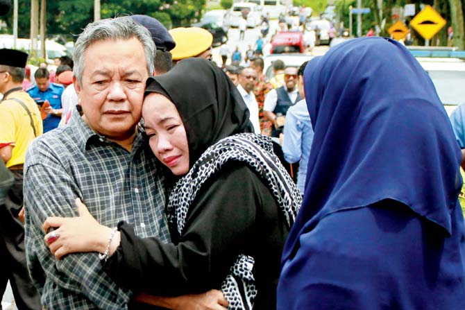 Nik Azlan Nik Abdul Kadir (L), father of one of the victims comforts his wife. Pic/AFP