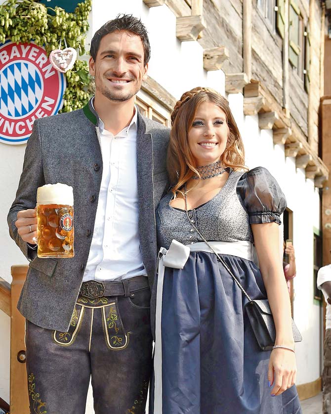 Mats Hummels holds a beer mug as he poses with his partner Cathy Fischer