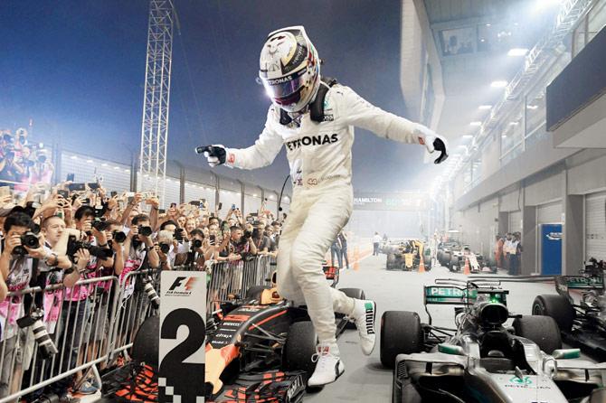 A victorious Lewis Hamilton jumps off his Mercedes