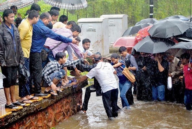 Mumbaikars help stranded passengers get on safer grounds at a railway station during the deluge that followed heavy rains on August 29. Pic/Datta Kumbhar