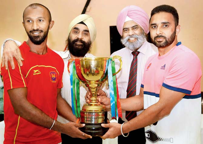 Indian Oil captain Deepak Thakur (right) and South Central Railway skipper MG Poonacha pose with the Guru Tegh Bahadur Gold Cup after both teams were declared joint winners yesterday