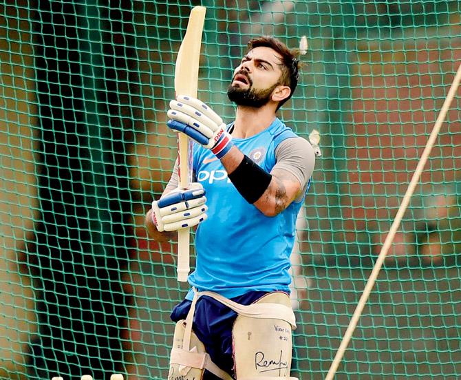 India skipper Virat Kohli examines the bottom portion of his bat during a practice session at the M Chinnaswamy Stadium ahead of today