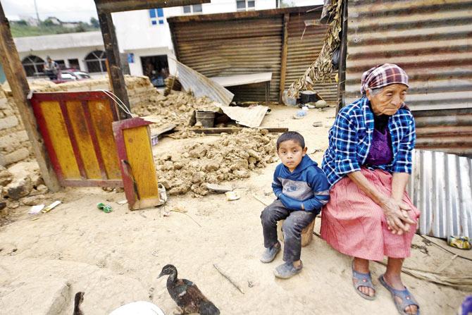 Local residents sit amidst damage caused by the earthquake