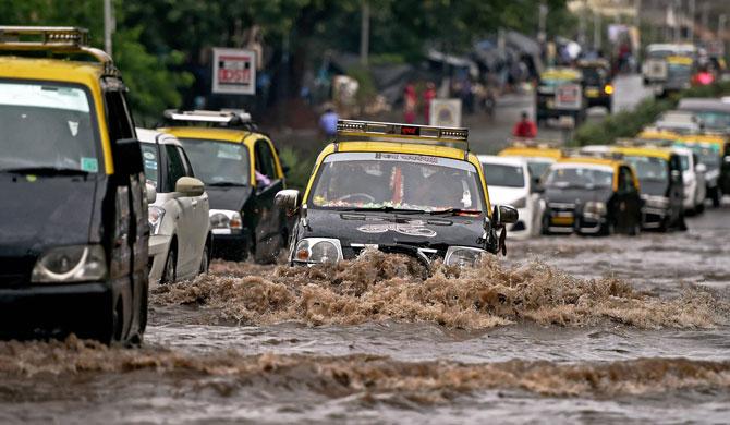  Vehicles wade through a water logged street after heavy rain in Mumbai on Wednesday