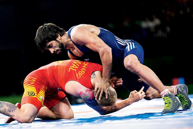 Bajrang Punia (in blue) wrestles with Wales’ Kane Charig in the freestyle 65kg final yesterday. Pic/AFP