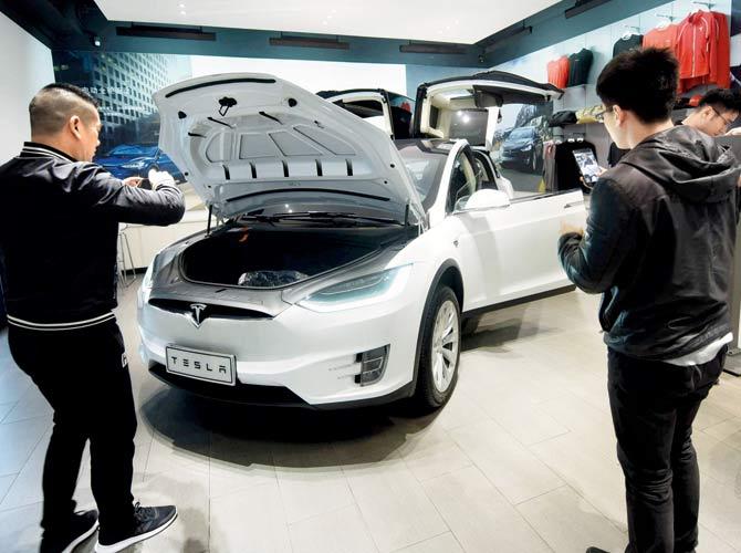 Customers look at Tesla cars in Hangzhou in China. China is ready to pay any cost in a trade war after Donald Trump threatened an additional $100 billion in tit-for-tat tariffs on Beijing.  Pic/AFP/China OUT