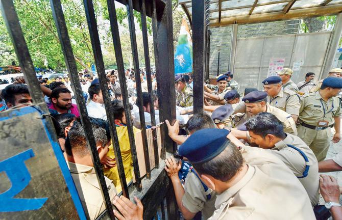Police personnel hold the gates as NSUI members try to gain access inside Shastri Bhawan during a protest against the alleged CBSE paper leaks, in New Delhi, on Monday. Pic/PTI