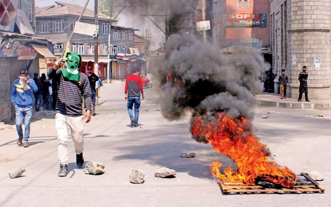 Kashmiris stand along a barricaded street during unrest following gunfights between suspected militants and police forces in South Kashmir, in Srinagar, on Sunday. Pic/AFP