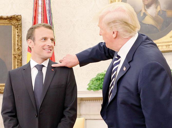 Donald Trump (right) clears dandruff off Emmanuel Macron