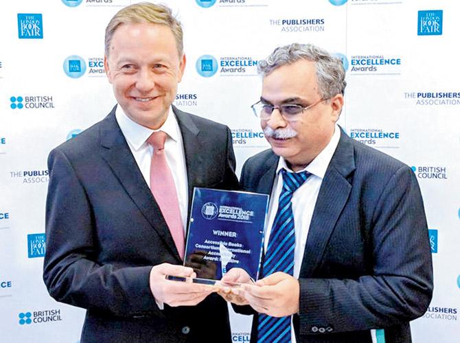 Dipendra Manocha (right), the president of DFI, accepts the award