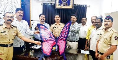 The police with the artificial butterfly they recovered from the two who stole it