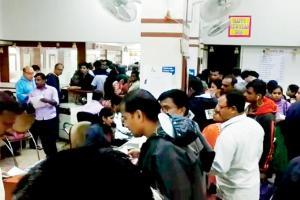 As ATMs remain shut, people queue up at branches to get money