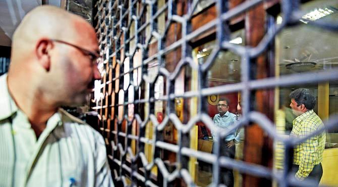 A man looks through the grille as a CBI team seals PNB